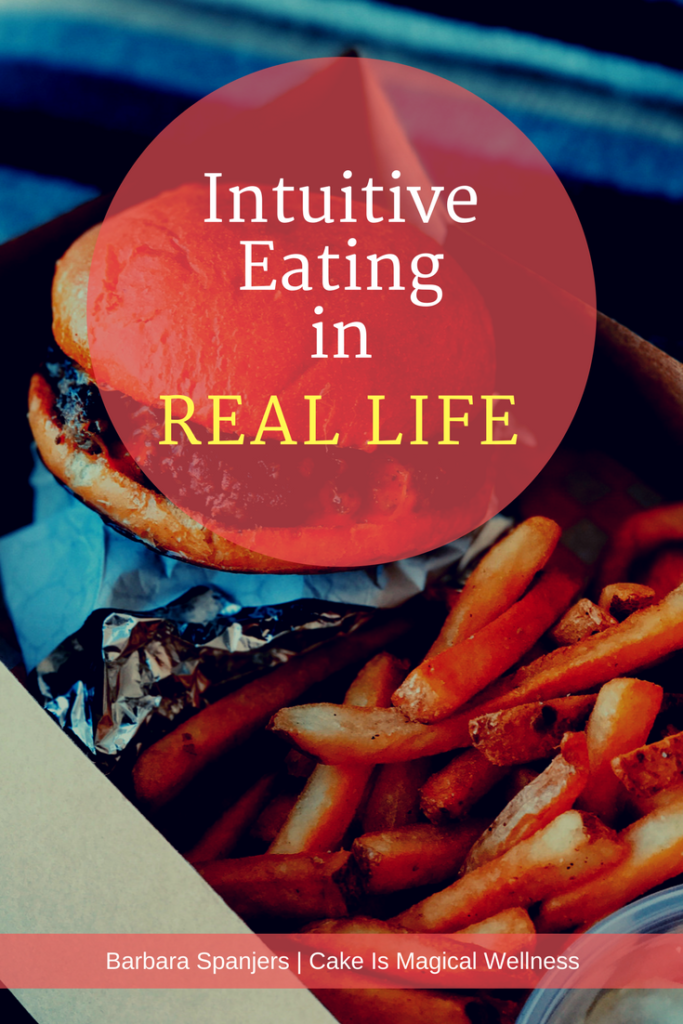 Close up of hamburger and fries in cardboard takeout box. Text overlay, "Intuitive Eating in Real Life"